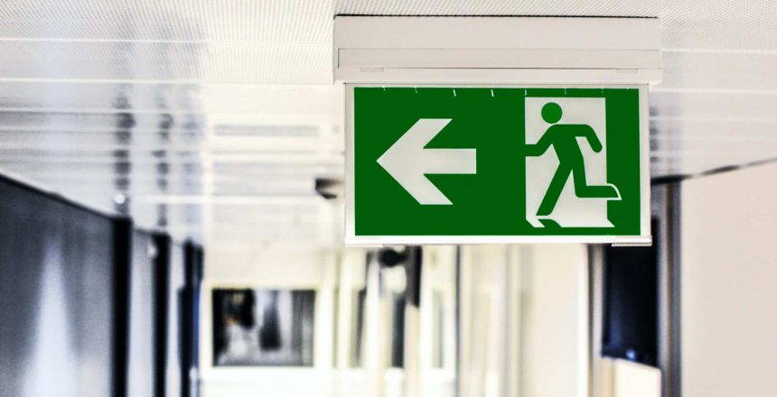 Green fire exit sign attached to ceiling